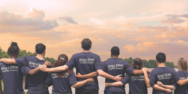 Photo of TowneBank Employees Embracing One Another Wearing Serving Others and Enriching Lives volunteer shirts