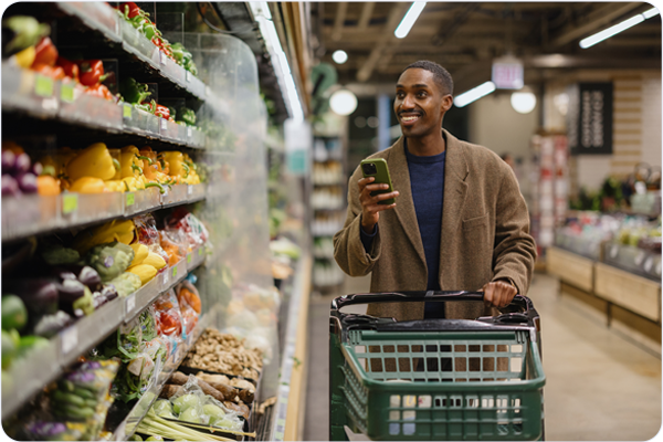 Man in grocery store looking at digital coupon on phone.