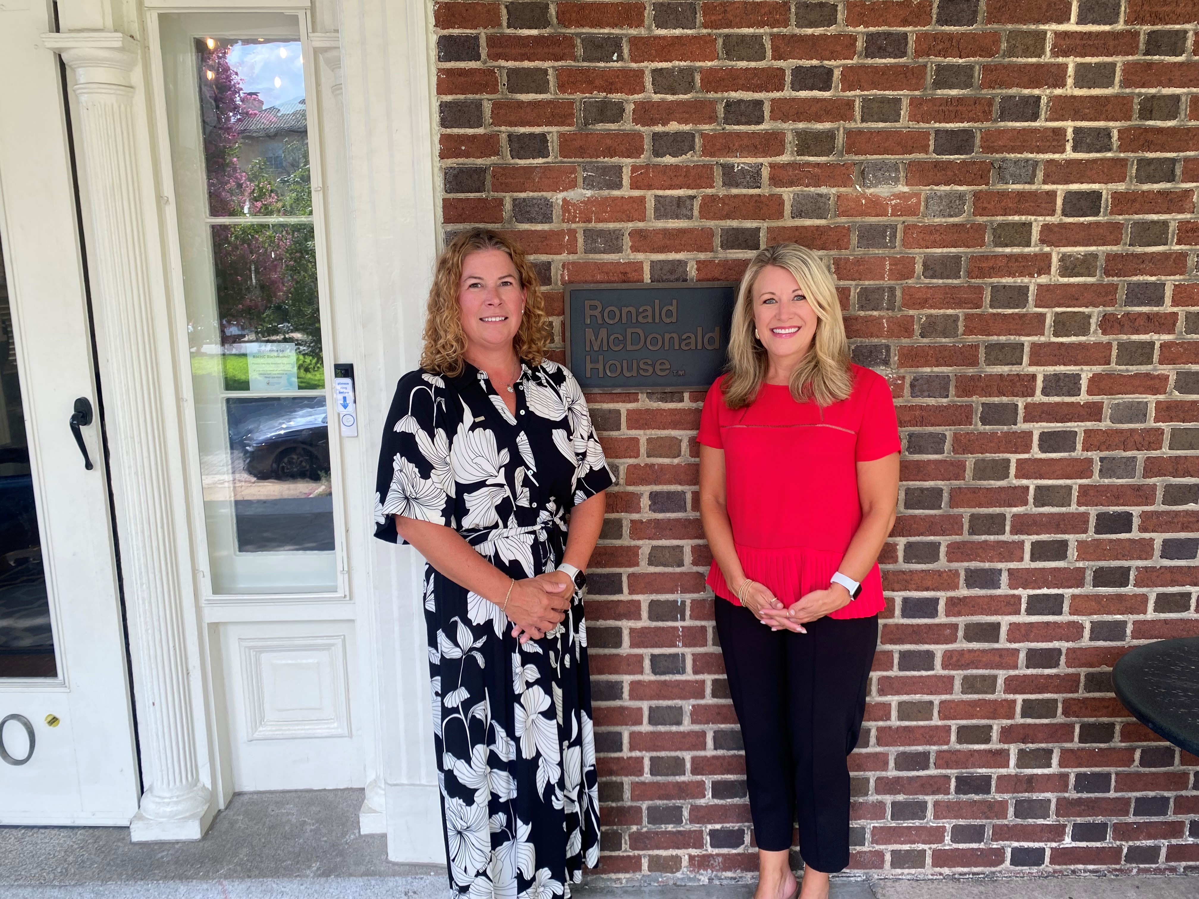 two woman standing in front of ronald mcdonald plaque