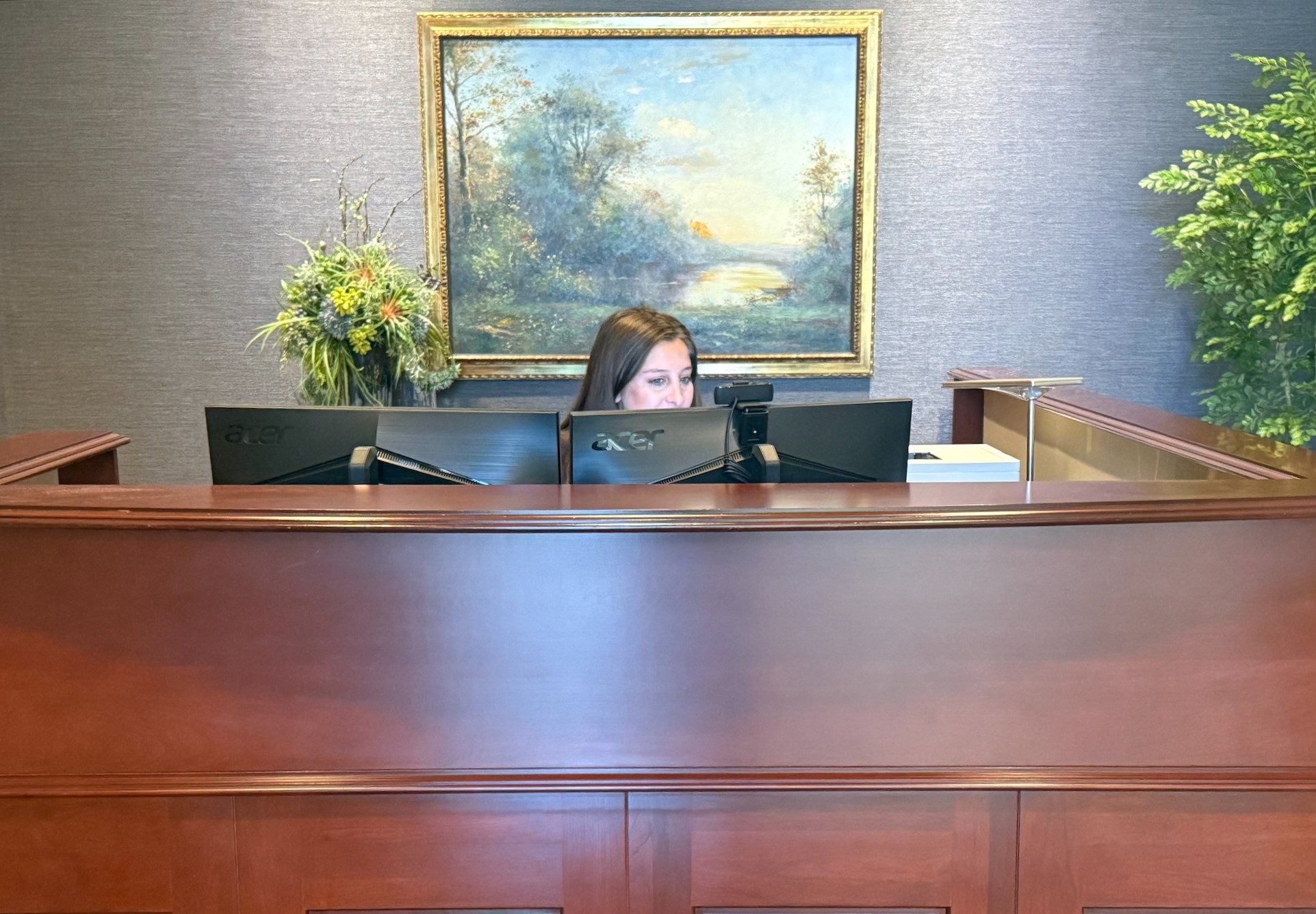 a woman sitting at a desk with a painting behind her