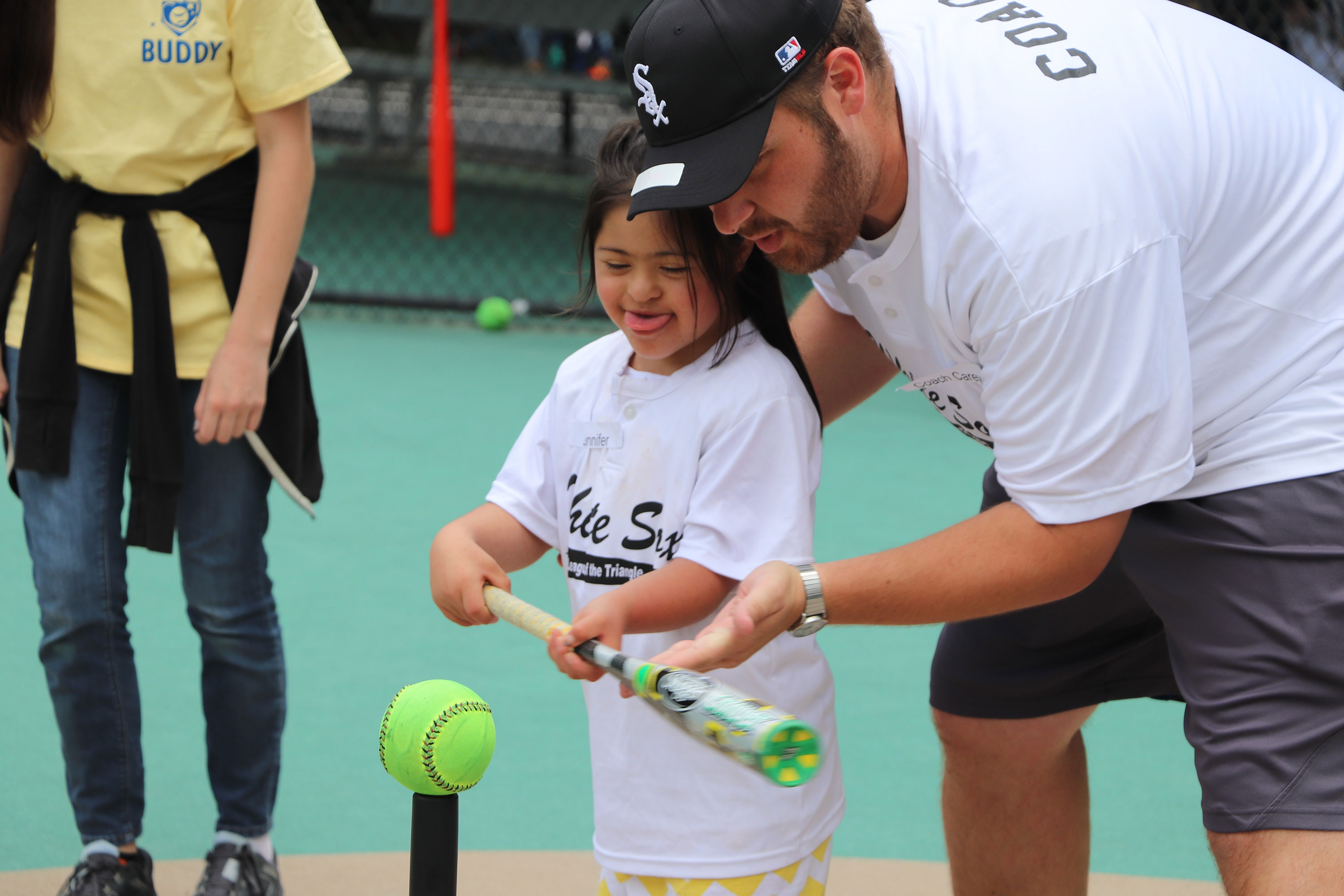 man showing young girl how to hit a t-ball