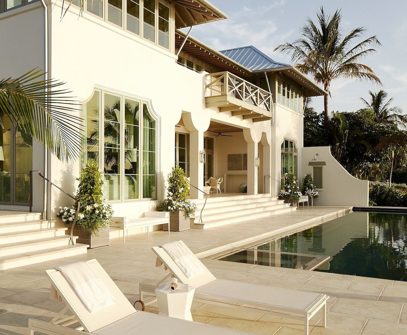 a white house with pool chairs and a pool