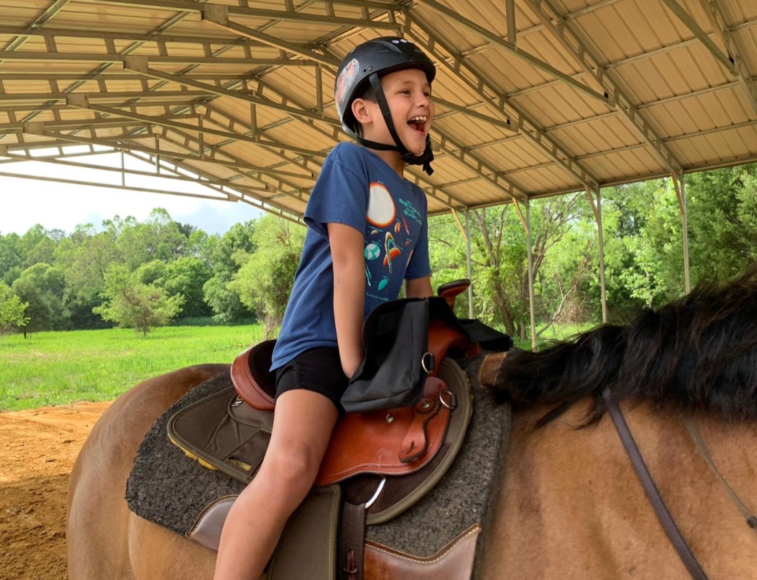 Photo of excited child riding a horse.