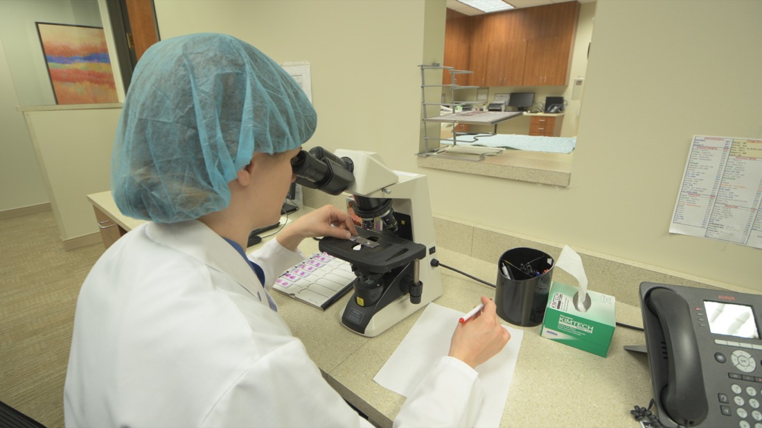 Photo of medical worker looking into a microscope.