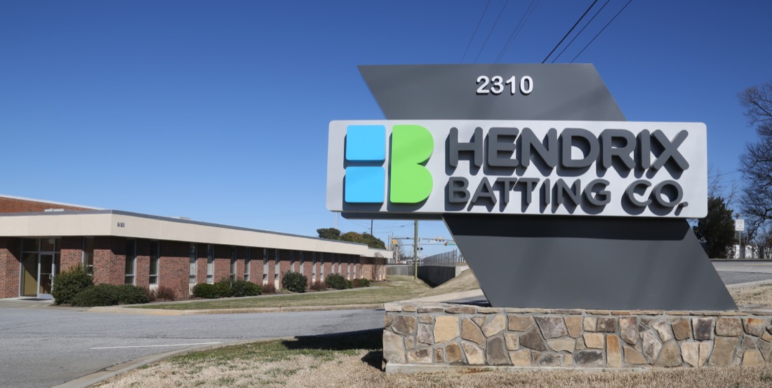 Hendrix Batting company sign with building in background.