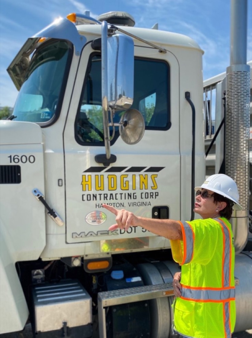 Contruction worker pointing to the left with truck in background