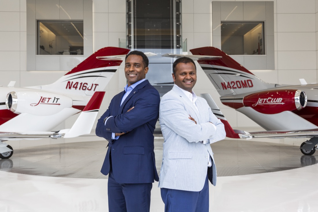 Two men standing back to back in an airplane hangar.