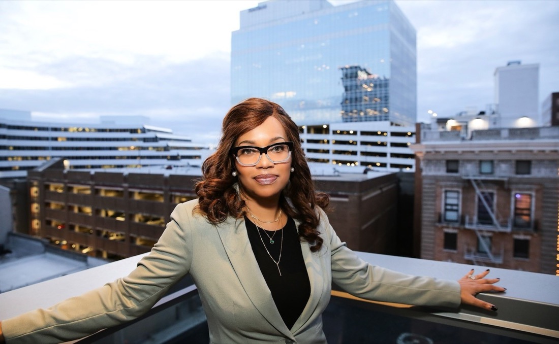 Photo of Angela Reddix with group of buildings in background.