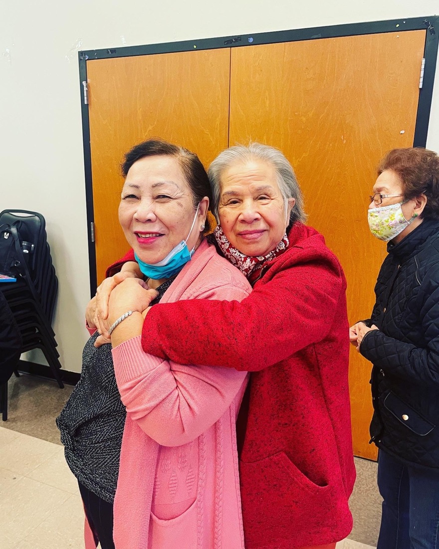 Two elderly women smiling and embracing.