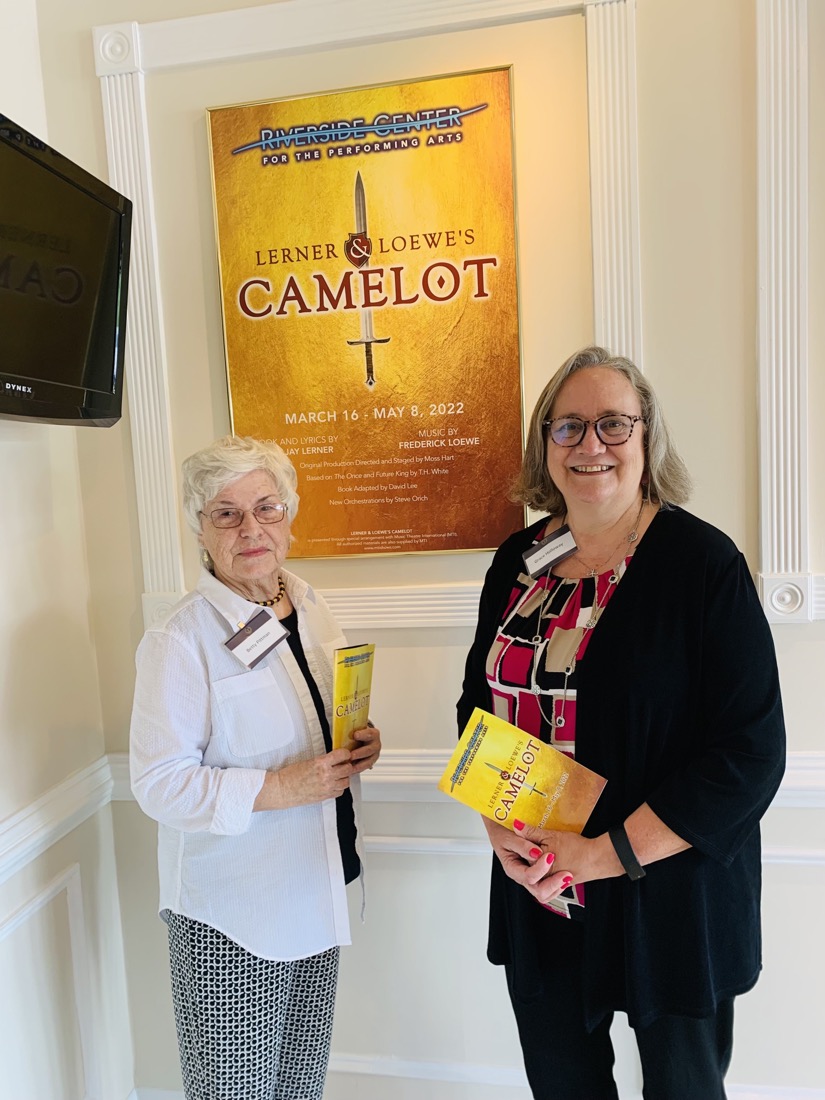 Two people holding programs and standing in theatre lobby.